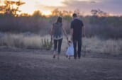 幼い子供と両親が手を繋いで歩く後ろ姿