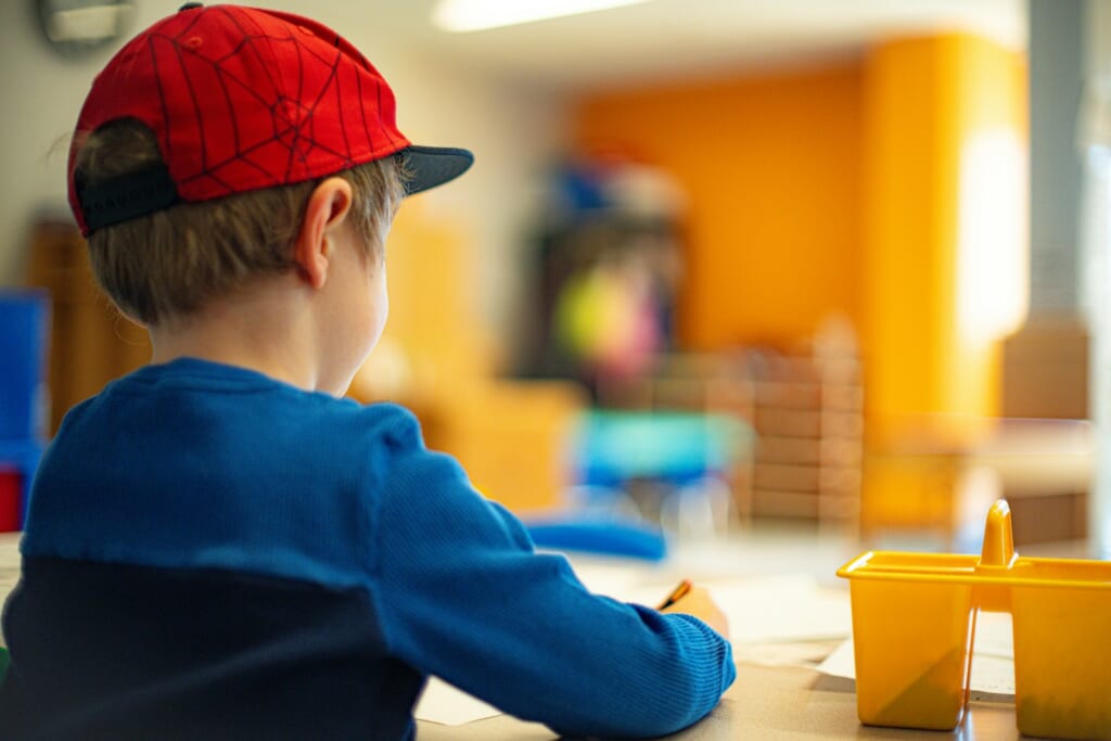 a young boy sitting at a table writing on a piece of paper