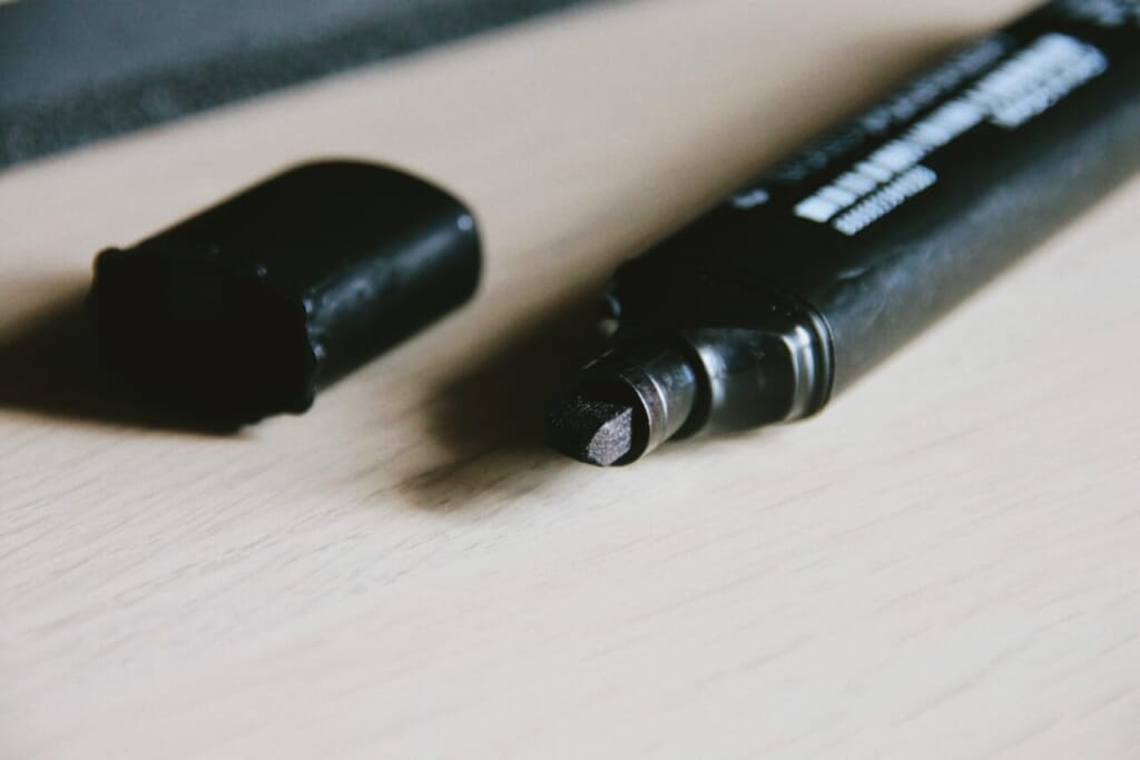 two black pens sitting on top of a wooden table