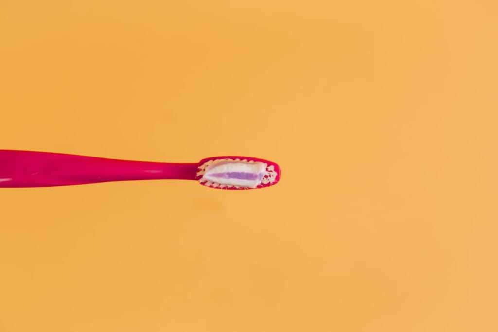 pink and yellow toothbrush on orange background