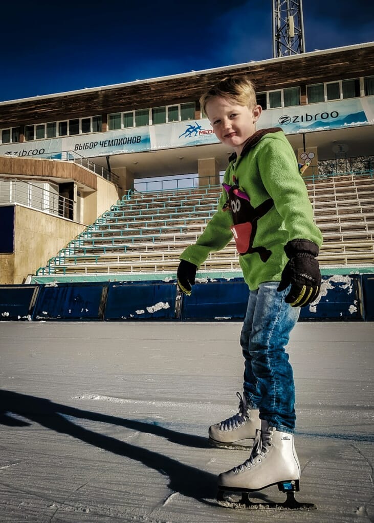 a young boy riding a skateboard in front of a stadium