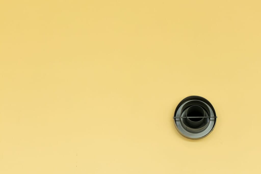 a yellow wall with a black round object on it