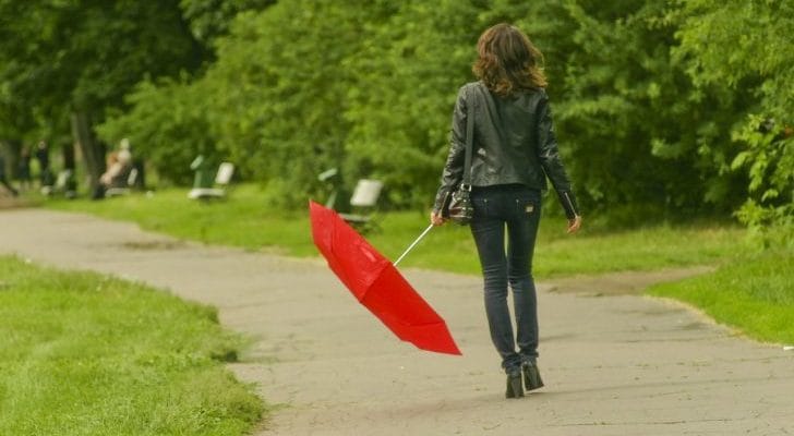 折りたたみ傘を持った女性の後姿の画像