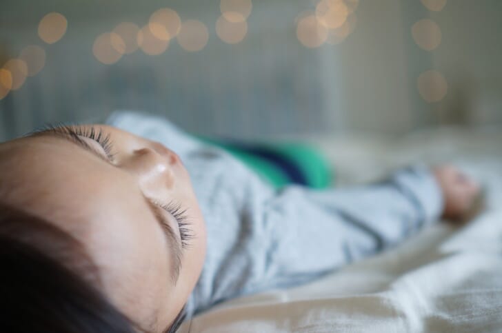 ベッドですやすや眠る子供の写真